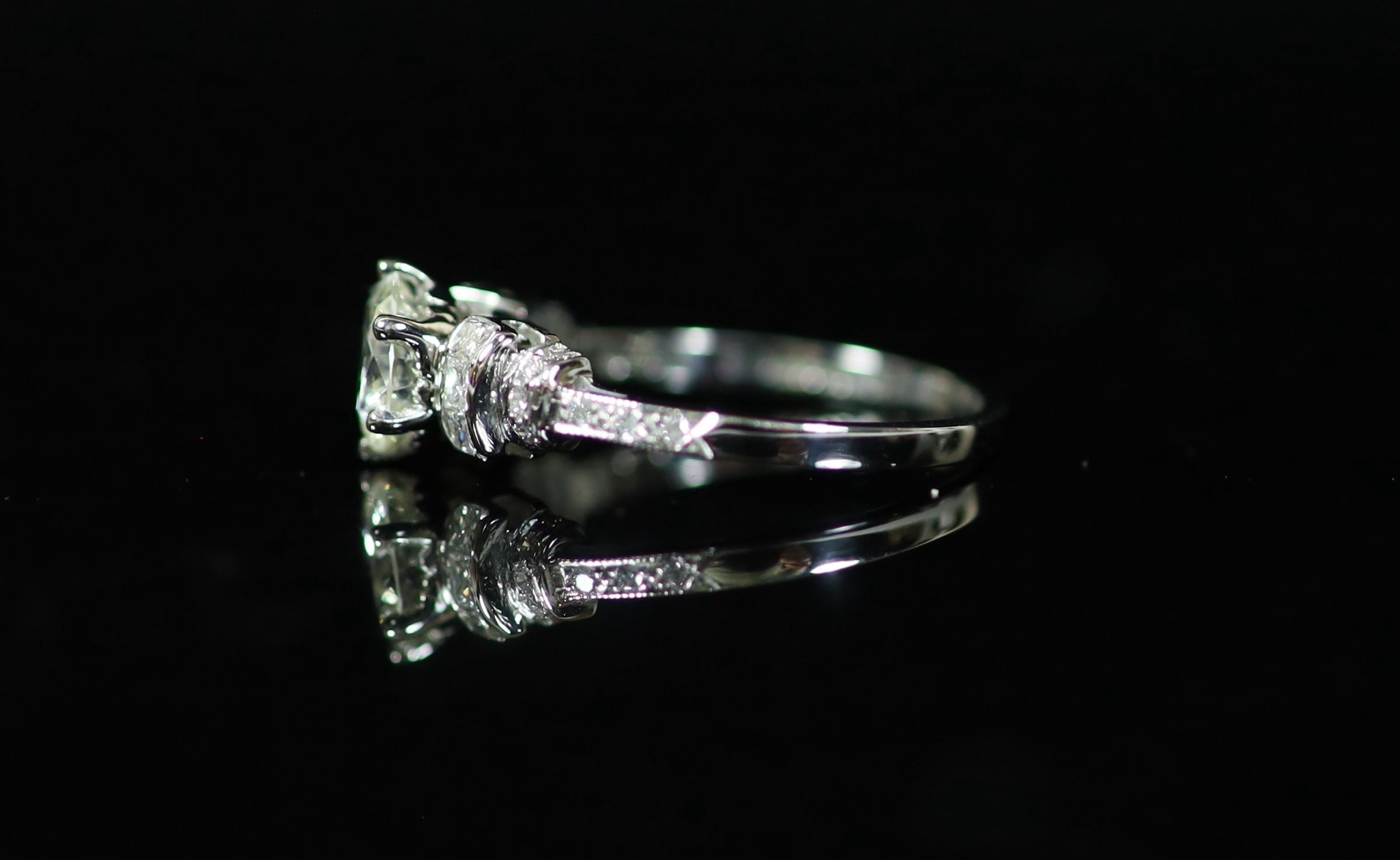 A modern platinum and single stone diamond ring centre with fancy and round cut diamond set shoulders